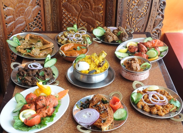 A diverse family dinner spread, square shot of South Indian dosas, North Indian tandoori, and traditional meat curries at Karaikudi Restaurant in Toronto